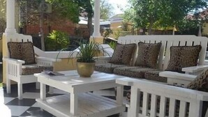Un patio con un conjunto de sofá blanco, una mesa de centro y una planta en maceta.