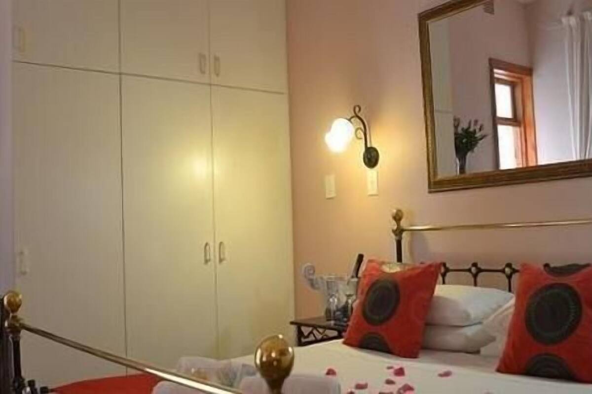 A bedroom with a bed, a wardrobe, a mirror, and a wall-mounted light fixture.