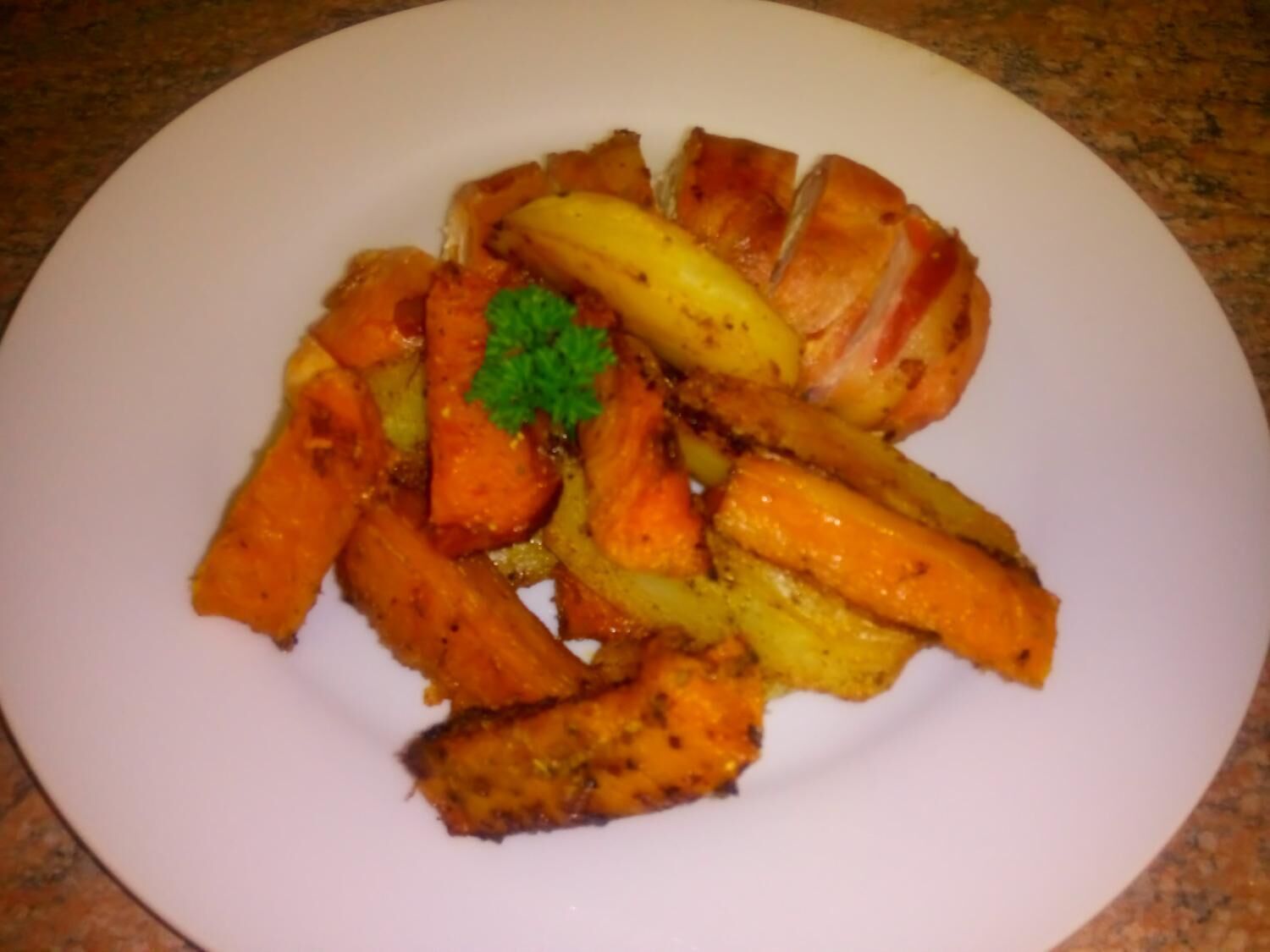A plate of roasted vegetables including carrots, potatoes, and possibly sweet potatoes, garnished with parsley.