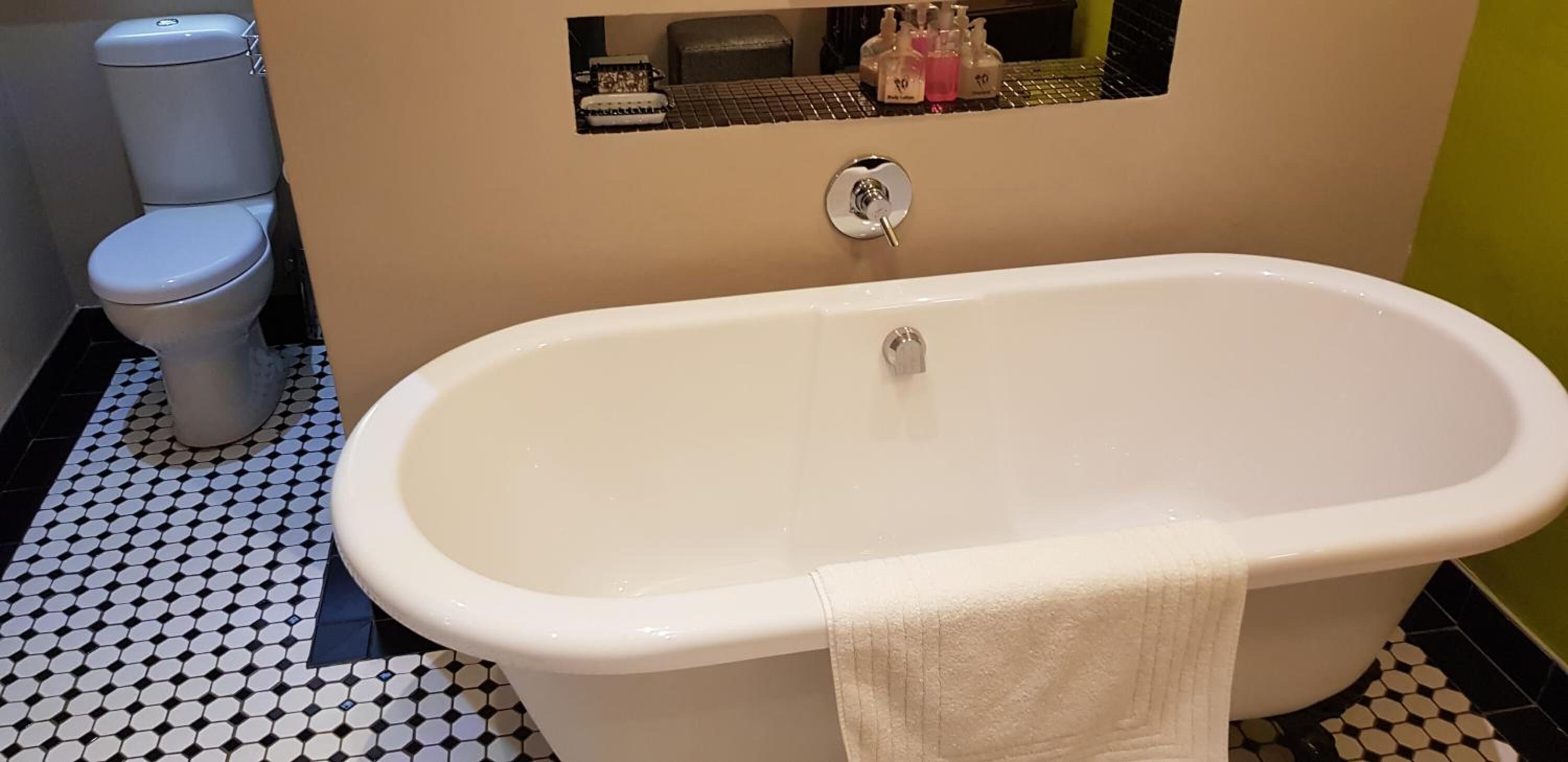 A bathroom with a white bathtub, a toilet, and a sink with soap dispensers.