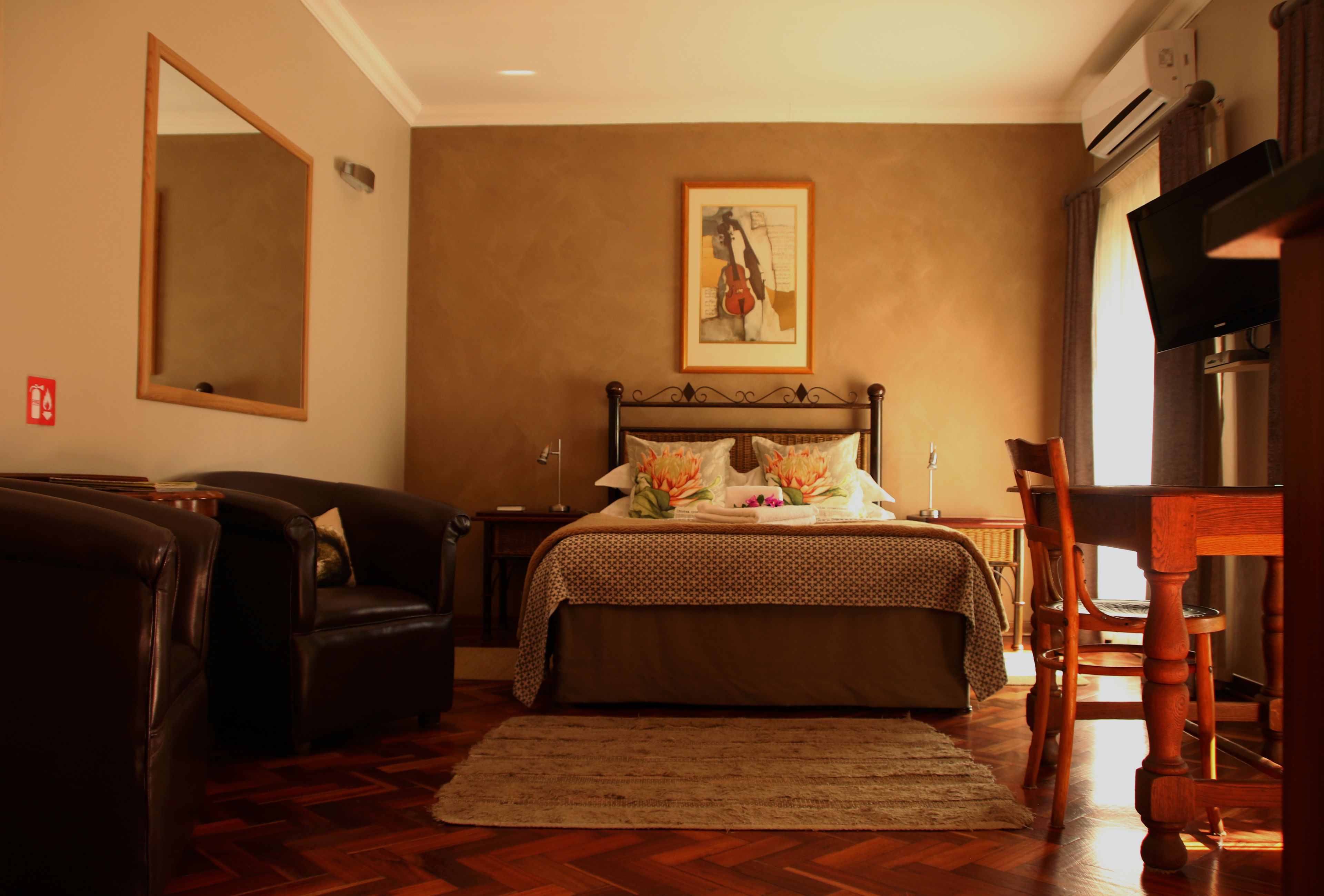 Ein Schlafzimmer mit Bett, Sessel, Sofa, Fernseher und einem Bild an der Wand.
