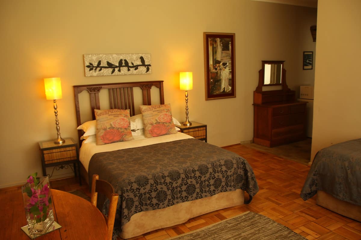 A bedroom with a wooden bed, two bedside tables with lamps, a dresser, and a mirror.