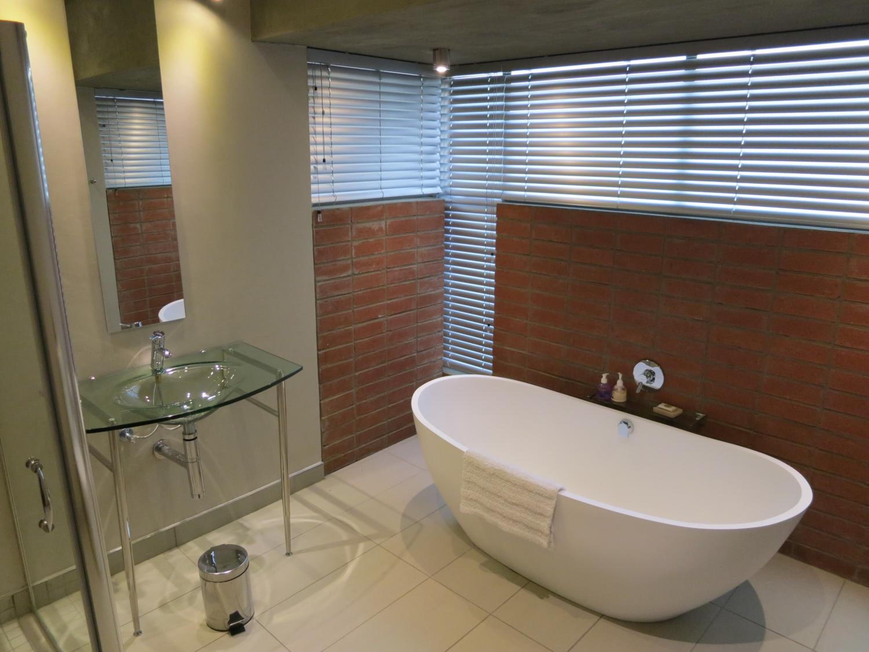 A modern bathroom with a glass sink, a freestanding bathtub, and a mirror.