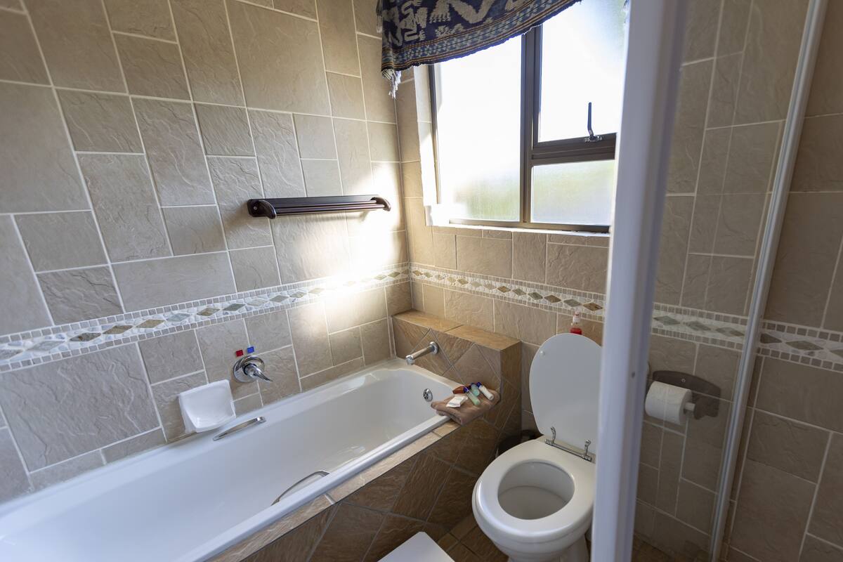 A bathroom with a bathtub, toilet, and a window.