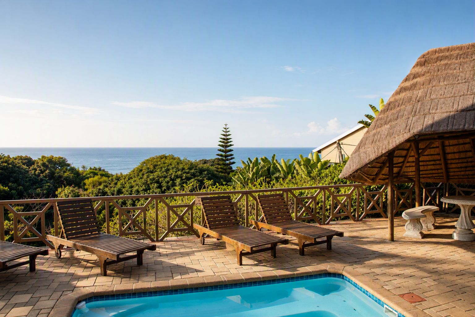 A pool area with lounge chairs and a thatched-roof structure.