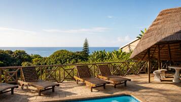 A pool area with lounge chairs and a thatched-roof structure.