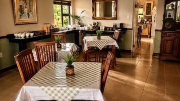 Un comedor con mantel a cuadros, sillas de madera y una planta en maceta.