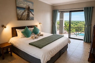 Habitación de hotel con cama, mesita de noche, un cuadro, un cartel de recepción y un balcón con vistas.