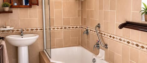 A bathroom with a bathtub, a sink, a shower, and a mirror.