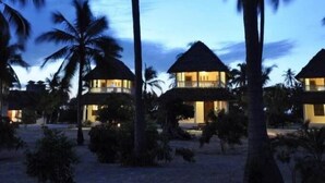 A resort with multiple bungalow-style buildings, palm trees, and a beach setting. - Kijongo Bay Beach Resort (Pangani)
