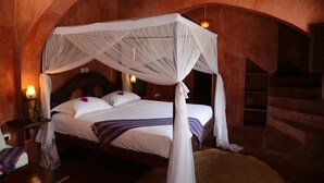 A bedroom with a canopy bed, wooden walls, and a staircase. - Kijongo Bay Beach Resort (Pangani)