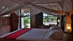 Ein Bett mit roter Decke, weißen Kissen und einem Baldachin.
