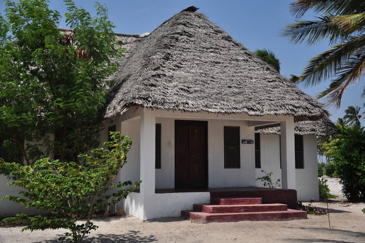 A small, single-story building with a thatched roof and a wooden door.