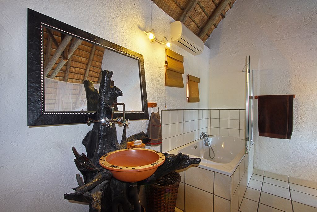 A bathroom with a large mirror, a bathtub, and a rustic sink.