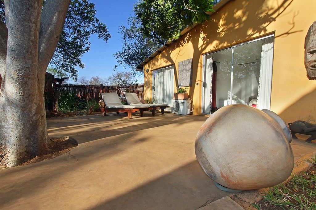 A patio with a concrete floor, a large rock, and a wooden fence.