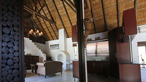 Una habitación con techo alto, una escalera, un sofá y una zona de cocina.