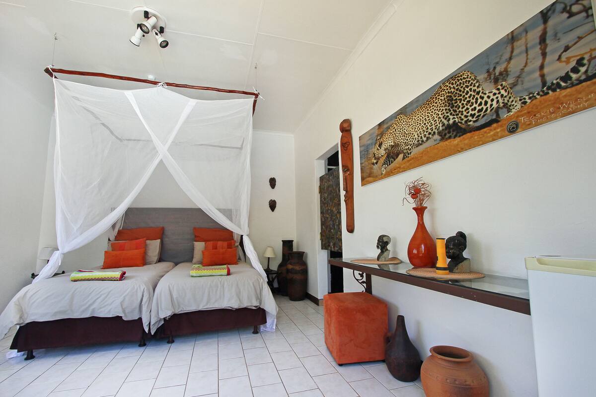Un dormitorio con cama con dosel, una mesita de noche y un cuadro de un leopardo.