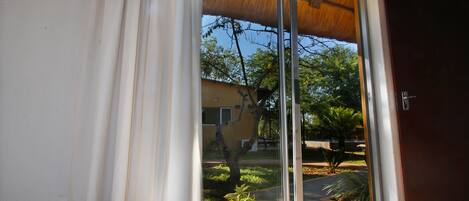 A sliding glass door with a view of a residential area, including a house and trees.