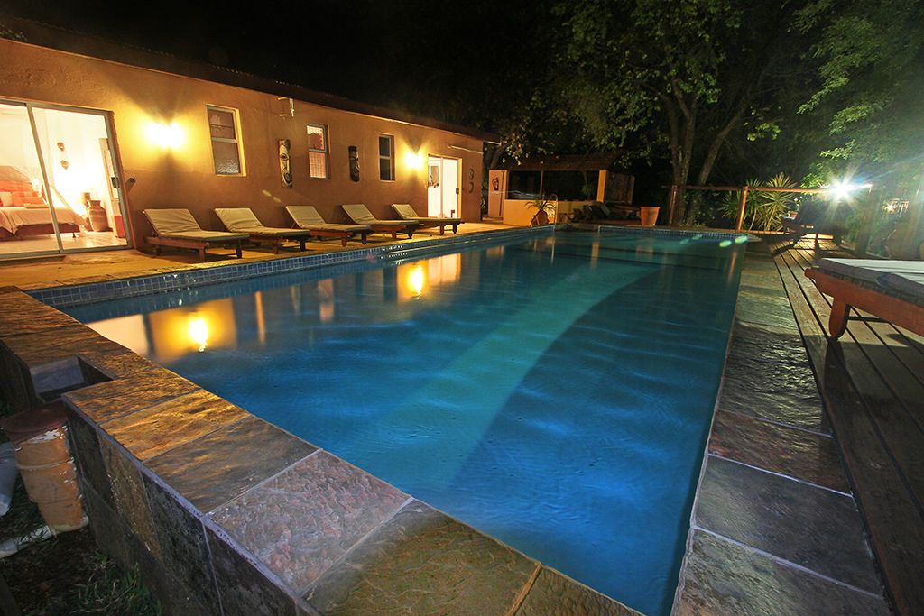 Una piscina con sillas de descanso y un edificio con puerta de cristal.