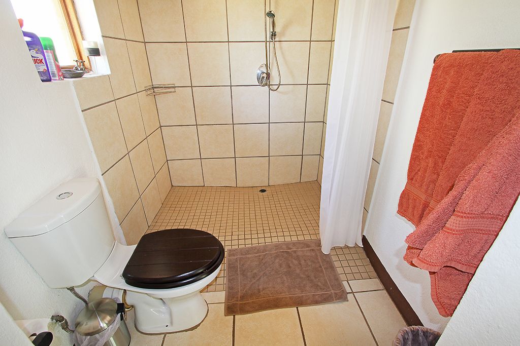 A small bathroom with a toilet, shower, and a towel rack.