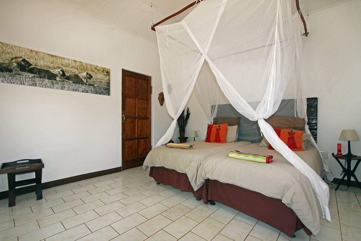Un dormitorio con cama con dosel, una puerta de madera, una mesita pequeña y una lámpara fijada a la pared.