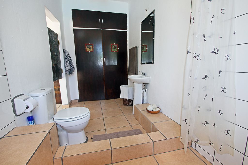 A bathroom with a toilet, sink, and dark wooden wardrobe.