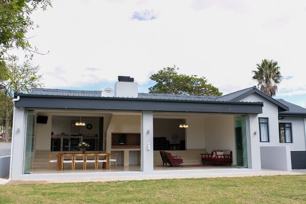A modern house with a covered patio, an open kitchen, and a dining area. - 401 Rozendal Cottages (Stellenbosch)