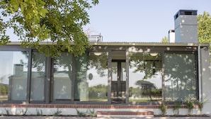 A modern glass house with a brick base, large windows, and a chimney. - 401 Rozendal Cottages (Stellenbosch)