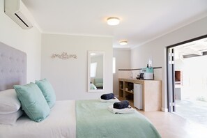 A modern bedroom with a bed, pillows, a bedside table, a mirror, and a view of the outside. - 401 Rozendal Cottages (Stellenbosch)