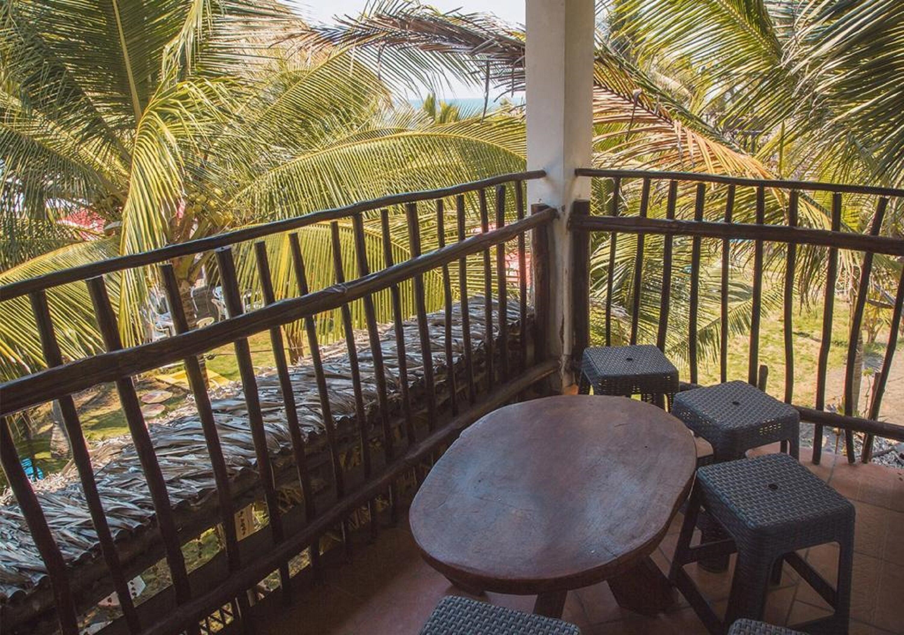 A balcony with a view of palm trees and a pool.