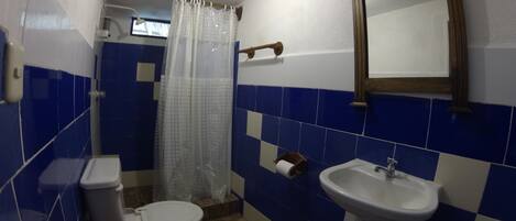 Un baño con inodoro, lavamanos y cortina de ducha.