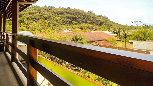 A balcony with a view of a hillside and buildings. - Pousada Montanhas do Bem TeVi (Caraguatatuba)