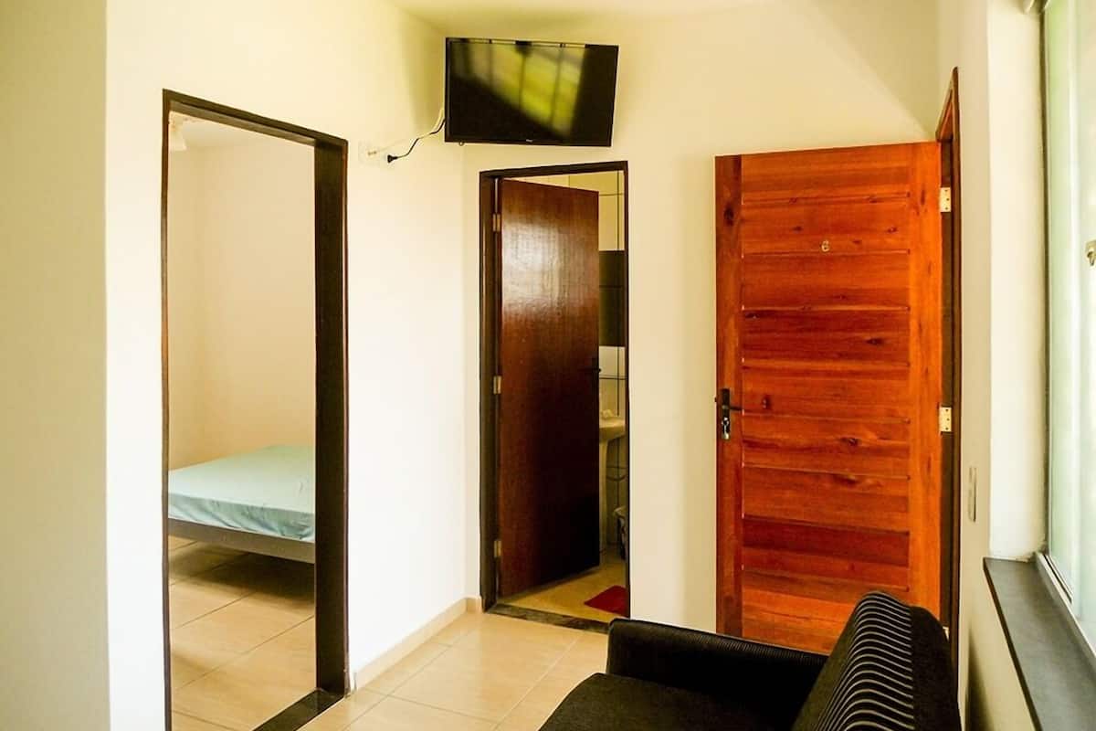 Een kamer met een bed, een aan de muur bevestigde televisie en een houten deur.