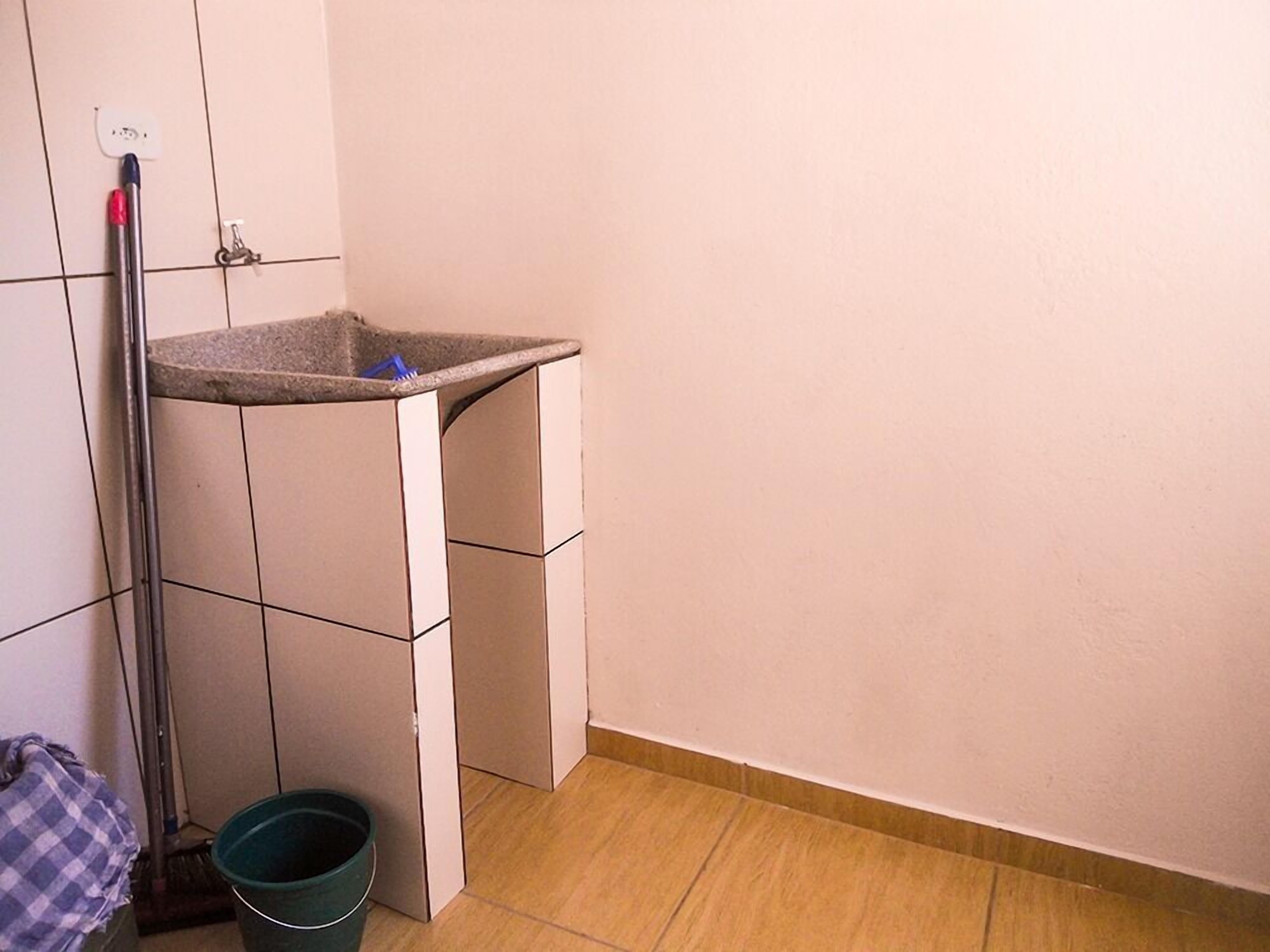 A small kitchen area with a sink, a broom, and a bucket.