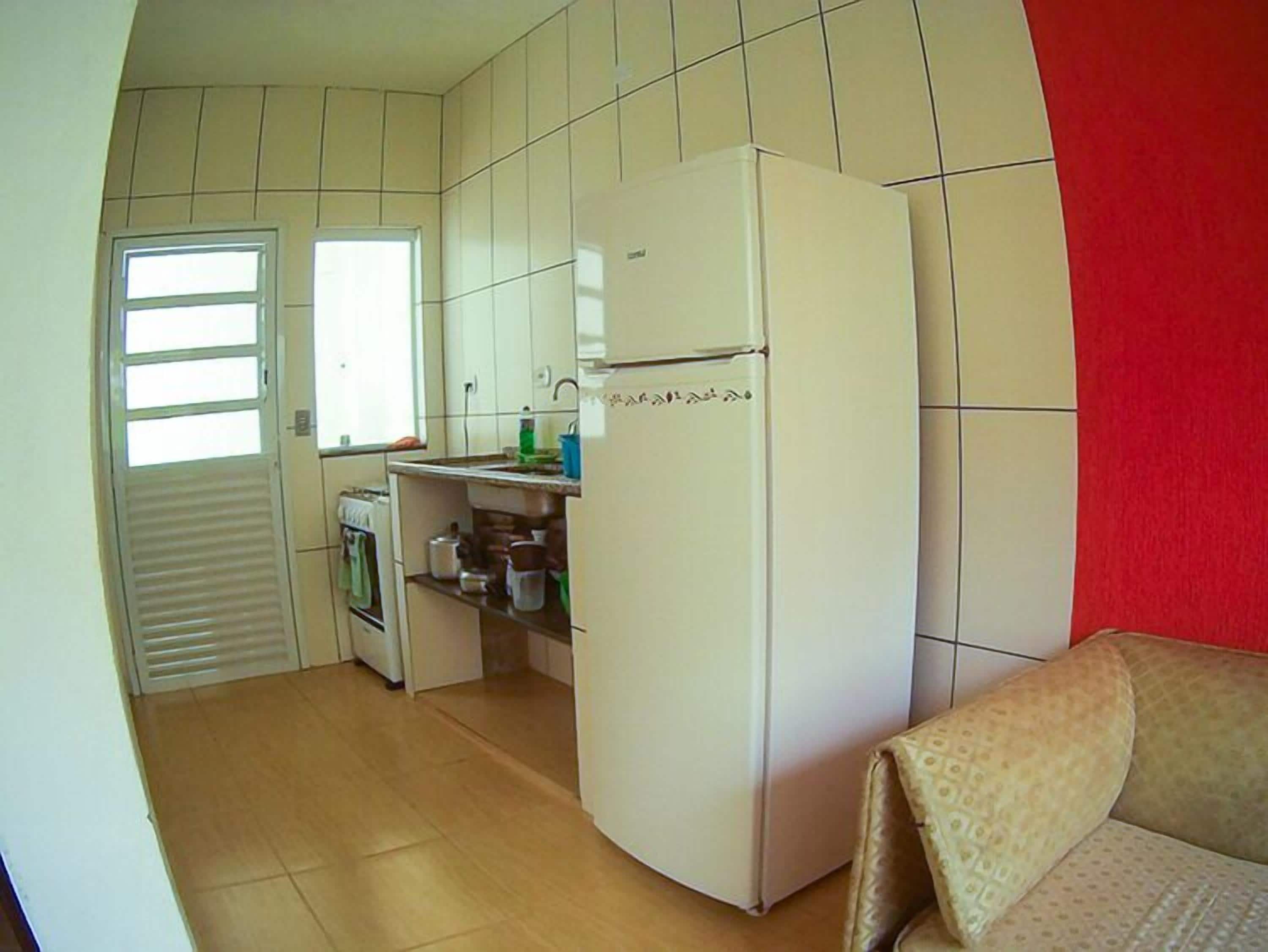 A compact kitchen with a refrigerator, a sink, and a window.