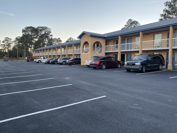 A motel with multiple parking spaces and a row of parked vehicles. - Capital Inn (Cordele)