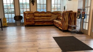 Una habitación amplia con un sofá modular grande, una silla negra, una mesita y una máquina expendedora.