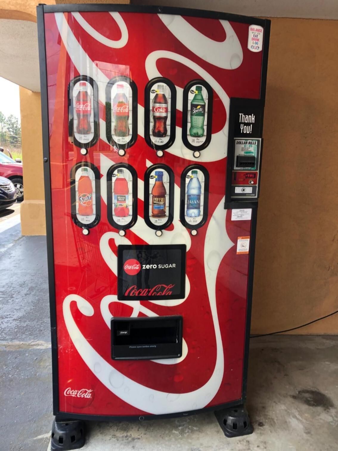 A Coca-Cola branded vending machine with multiple beverage options, a 'zero sugar' label, and a 'Thank You!' message.