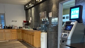 Una cocina moderna con cajero automático integrado, armarios de madera y una cafetera.