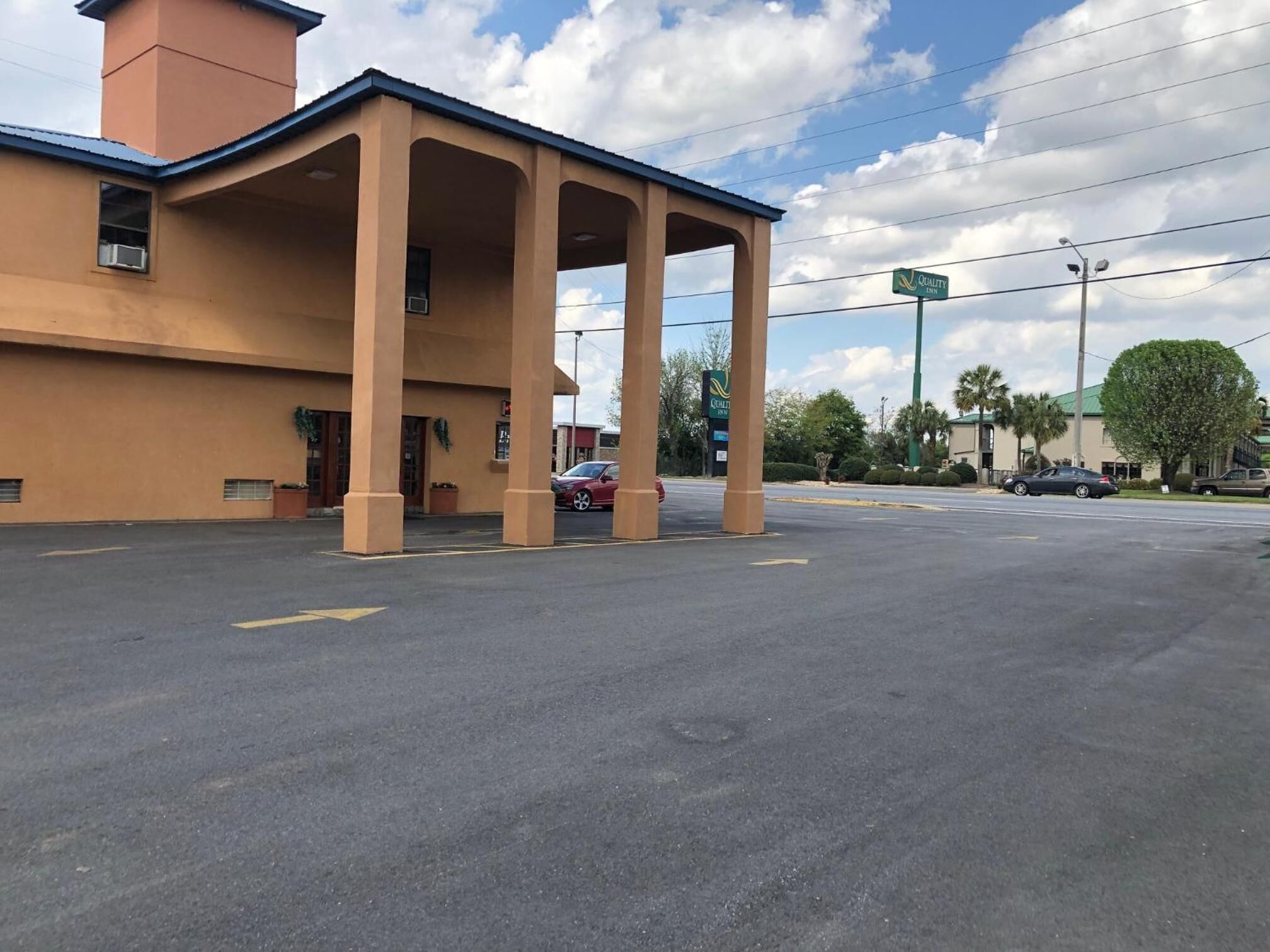 Un hotel con entrada techada, amplios pilares y estacionamiento.