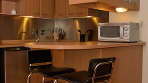 Una cocina moderna con armarios de madera, un microondas de acero inoxidable y dos taburetes de bar.