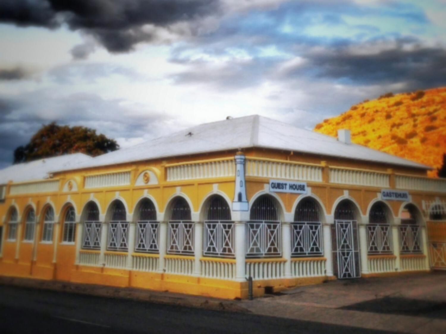 A yellow building with a sign reading "GUEST HOUSE" and "GASTHAUS".