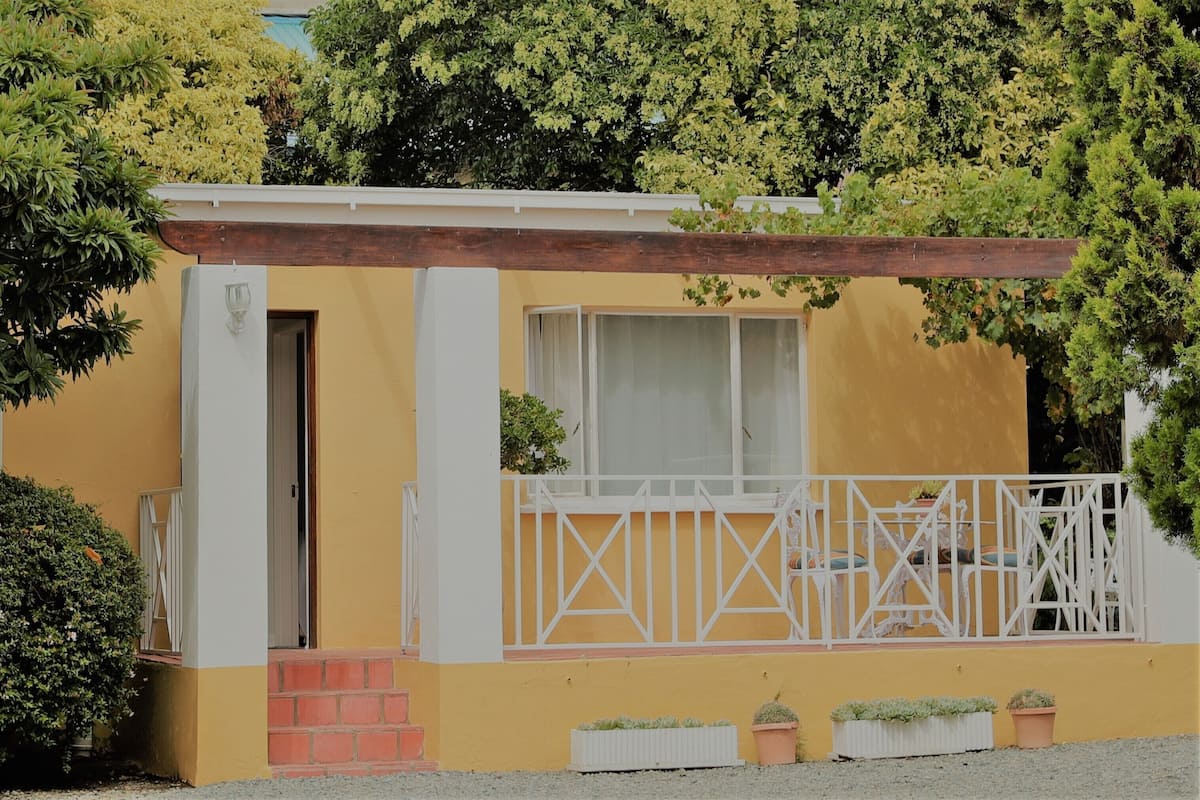 A small, yellow building with a white balcony and a wooden overhang.