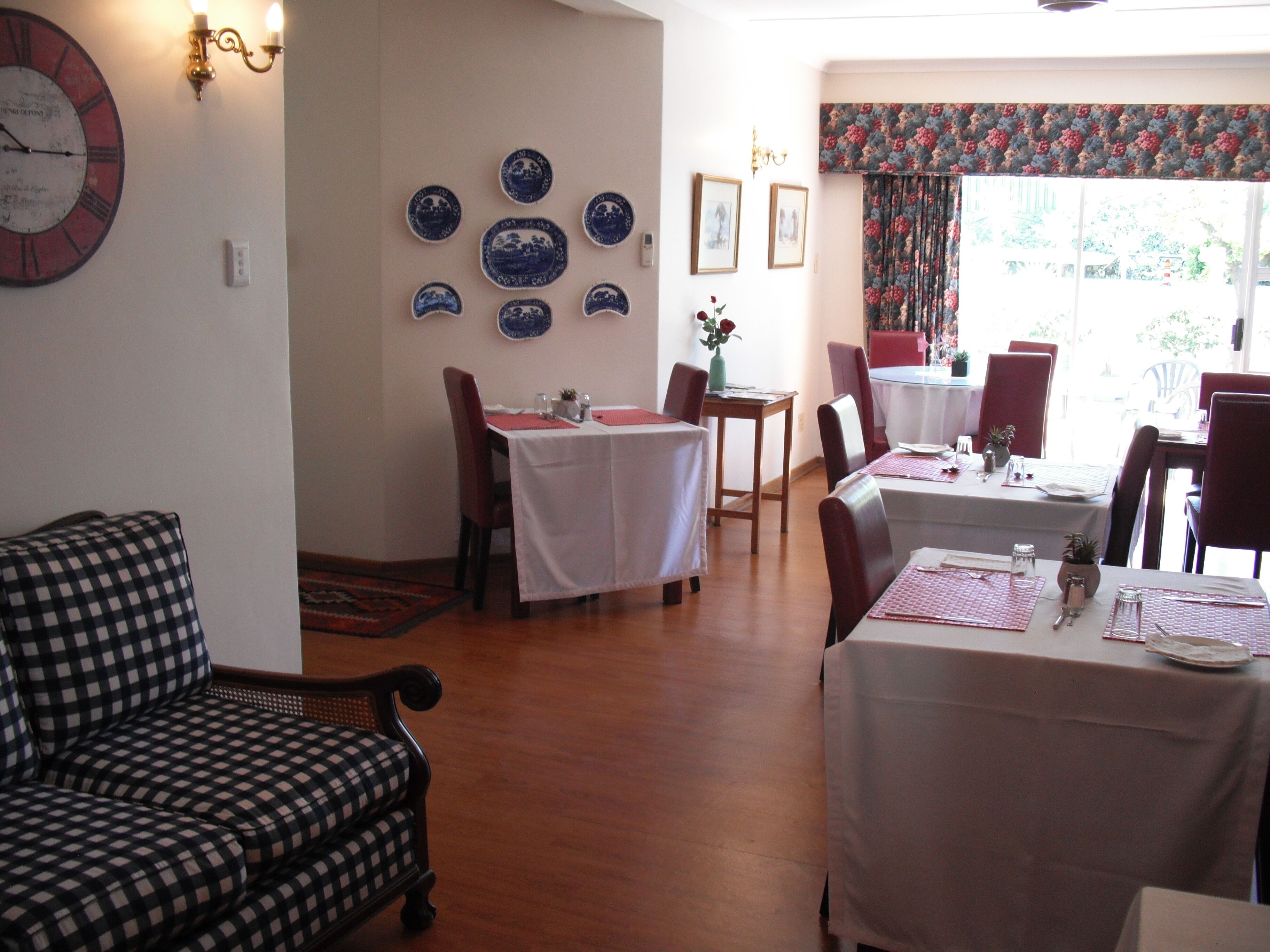 A dining area with checkered sofas, a dining table with a white tablecloth, and a wall decorated with blue and white plates.