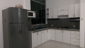 A modern kitchen with a refrigerator, microwave, sink, stove, and white cabinets.