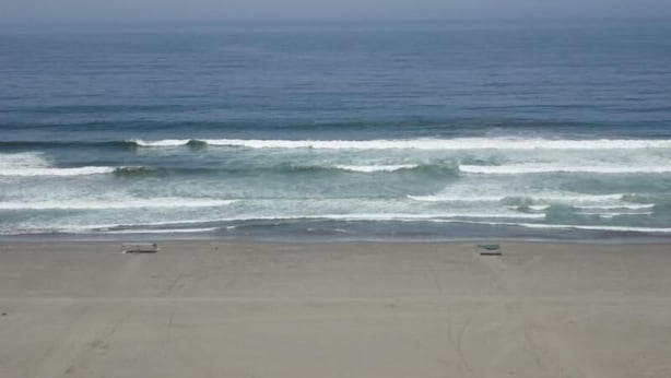A beach with waves and a clear sky.