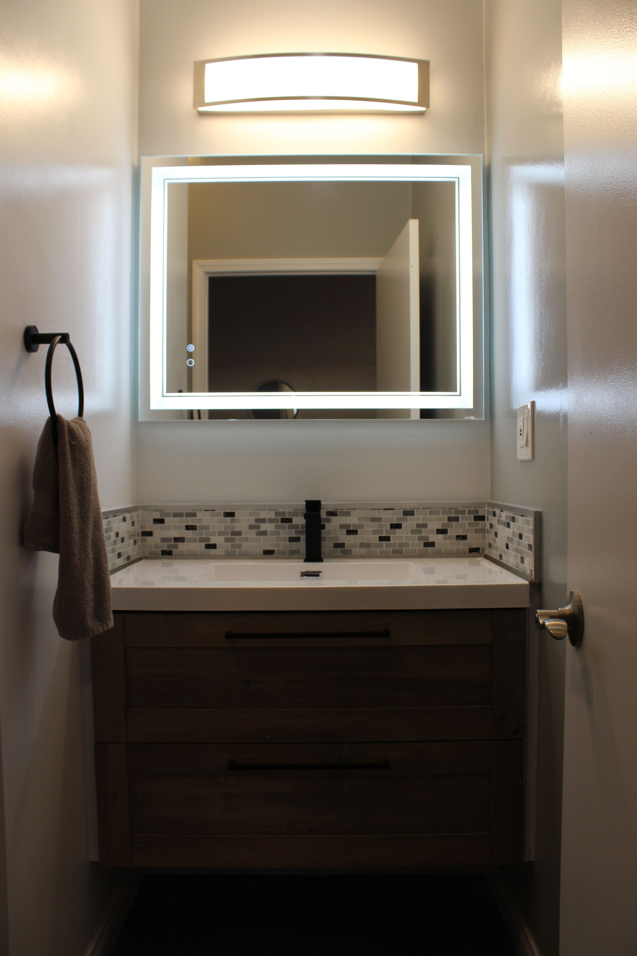 Un baño con espejo, lavamanos y barra para toallas.