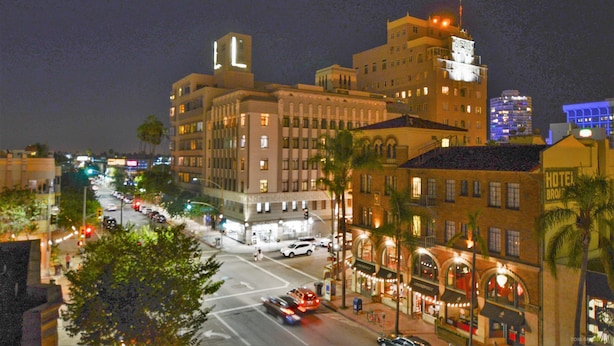 A hotel with multiple floors, a prominent tower, and a street view with cars and palm trees. - Hotel Royal (Long Beach)