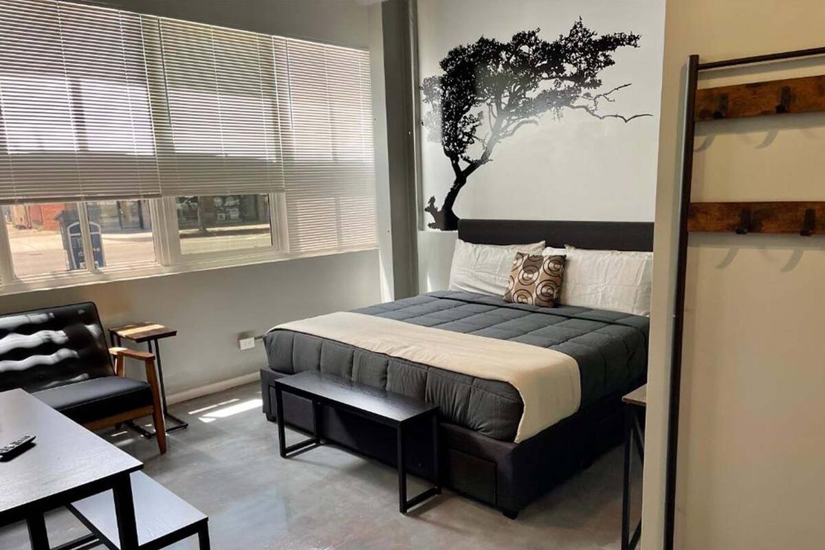 Un dormitorio con una cama, un escritorio, una silla y una ventana con persianas.