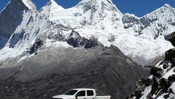 A white pickup truck parked in front of a snow-covered mountain range.